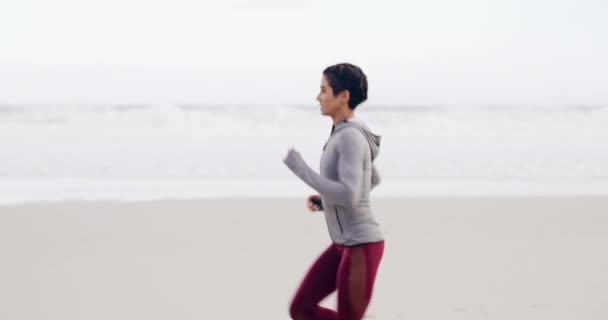 Fitness, hyvinvointi ja nainen käynnissä rannalla rodun, kilpailun tai maraton koulutusta. Urheilu, terveys ja nuori naisurheilija juoksija, jolla on kardioharjoitus tai liikunta hiekalla meressä tai merellä - Materiaali, video