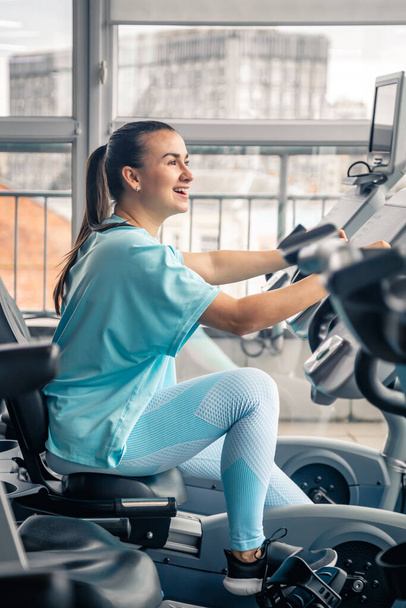 Fitness woman on bicycle doing cardio workout at gym, fit young female exercising on gym bike. - Photo, Image