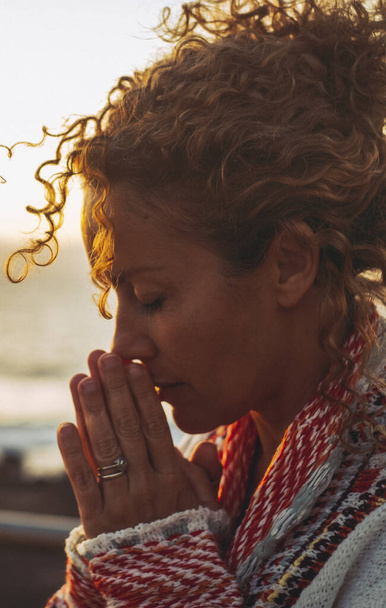 Meditasyon ve iç denge mutluluk kavramı, arka planda günbatımı okyanusuyla birlikte dua eden ve meditasyon yapan bir kadının yan portresi. Ruh sağlığı yaşam tarzı kavramı - Fotoğraf, Görsel