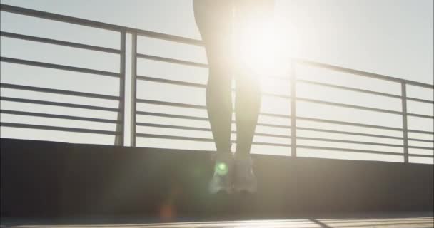 A vékony lábú női atléta ugrókötélre ugrik, miközben süt a nap. Fiatal nő magában foglalja ugrókötél rutinok napi fitness rend - Felvétel, videó