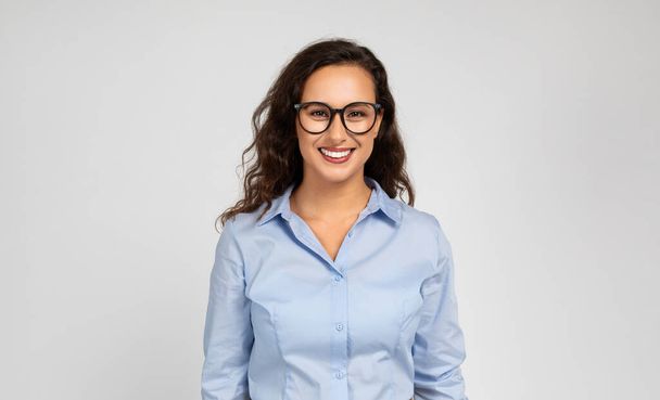 Позитивная молодая кавказская бизнесвумен, менеджер в формальной одежде, очки, изолированная на сером фоне студийного фона. Профессия, работа, учеба и бизнес - Фото, изображение