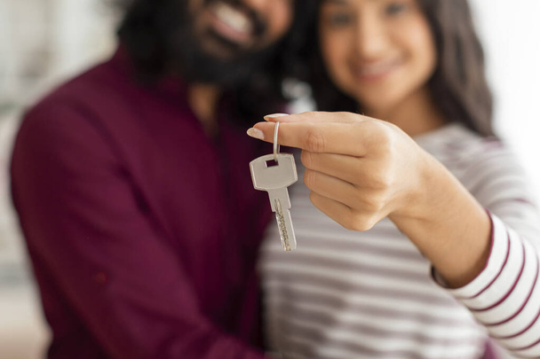 Selectieve focus op sleutel uit appartement in getrouwde paar handen. Indiase echtgenoten man en vrouw kocht nieuw huis, verhuizen naar een nieuw huis, wazig achtergrond - Foto, afbeelding
