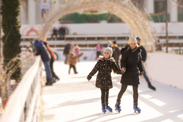 Adorable young mother with her daughter on the ice rink. - Foto, immagini