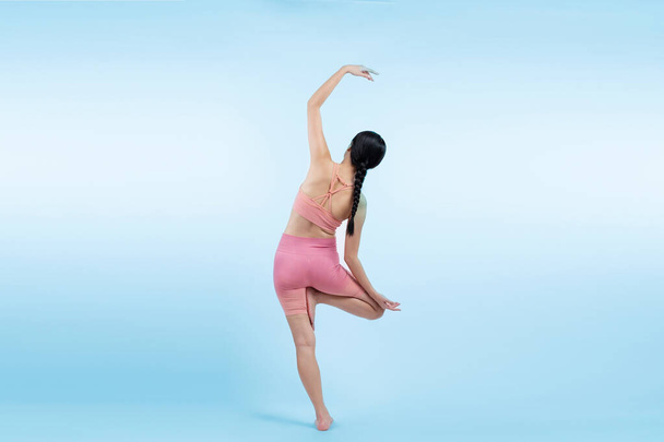 Spor kıyafetli Asyalı bir kadın antrenman yaparken ayakta durarak yoga egzersizi yapıyor. Sağlıklı vücut bakımı ve meditasyon yoga yaşam tarzı izole bir arka planda. Kuvvetli - Fotoğraf, Görsel