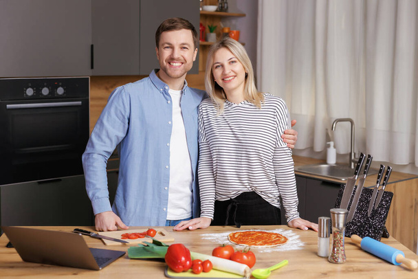 A boldog fiatal pár egészséges és ízletes ételeket készít a modern konyhában. Egészséges élelmiszer-koncepció - Fotó, kép