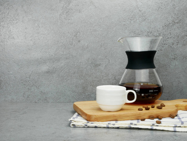 Кофе в стеклянном кувшине и чашка на подносе на фоне каменной текстуры. - Фото, изображение