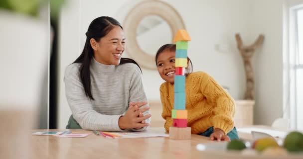 Мама грає з будівельними блоками зі своєю дочкою на кухні для розвитку дитини вдома. Щаслива, зв'язана і молода азіатська мати допомагає доньці з дерев'яними іграшками для розваги в їхньому будинку - Кадри, відео