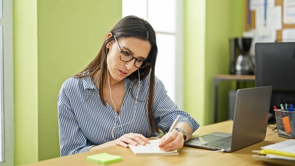 Młoda piękna latynoska kobieta biznes pracownik robi notatki myśląc w biurze - Zdjęcie, obraz