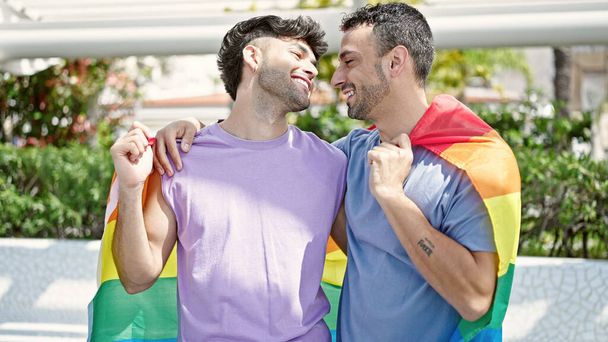 Twee mannen die elkaar knuffelen met een homoseksuele vlag in het park - Foto, afbeelding
