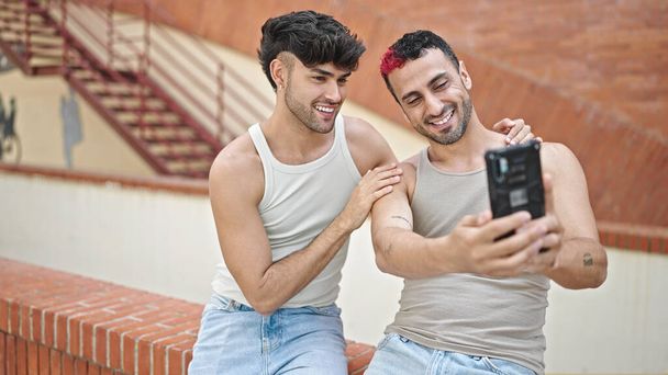 Двое мужчин улыбаются уверенно сделать селфи на смартфоне на улице - Фото, изображение