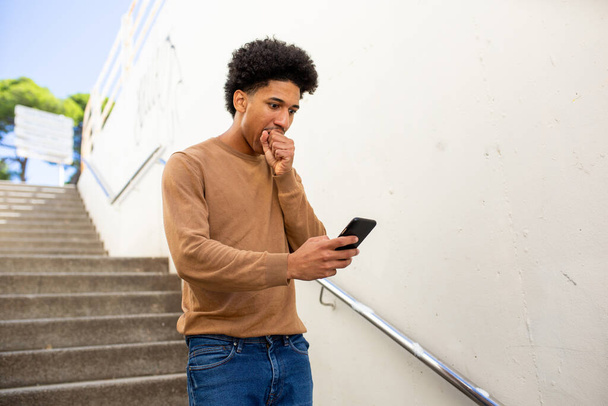 Портрет человека спускается по лестнице с мобильным телефоном в руке - Фото, изображение