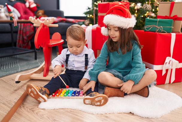 Чарівний хлопчик і дівчинка грають ксилофон, святкуючи Різдво вдома - Фото, зображення