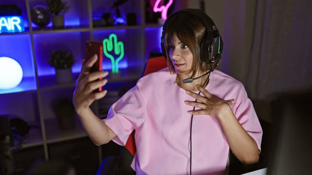 Young beautiful hispanic woman streamer smiling confident having video call at gaming room - Photo, image