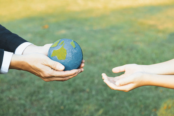 Бізнесмен дає земну кулю маленькому хлопчику як концепцію дня Землі як корпоративну соціальну відповідальність за внесок екологічного захисту для сталого майбутнього покоління. Гейр - Фото, зображення