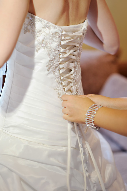 Bridesmaid is helping the bride to dress - Valokuva, kuva
