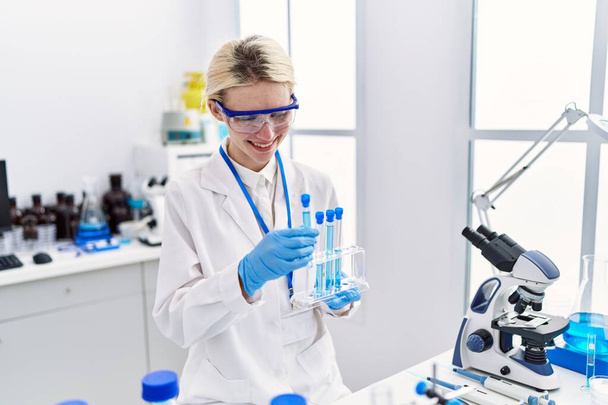 Nuori blondi nainen tiedemies analysoi koeputkia laboratoriossa - Valokuva, kuva