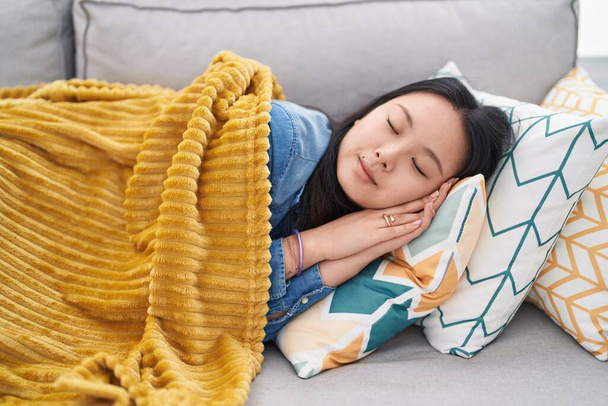 Joven mujer china tumbada en el sofá durmiendo en casa - Foto, Imagen