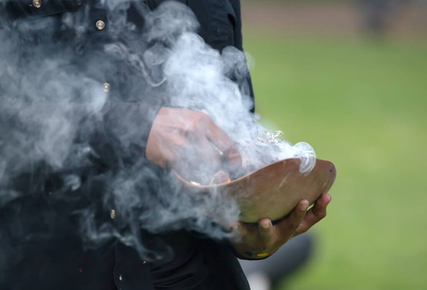 İnsan elleri, Avustralya 'daki yerel halk etkinliğinde dumanlı dallarla yapılan ahşap tören tabağını tutuyor. - Fotoğraf, Görsel
