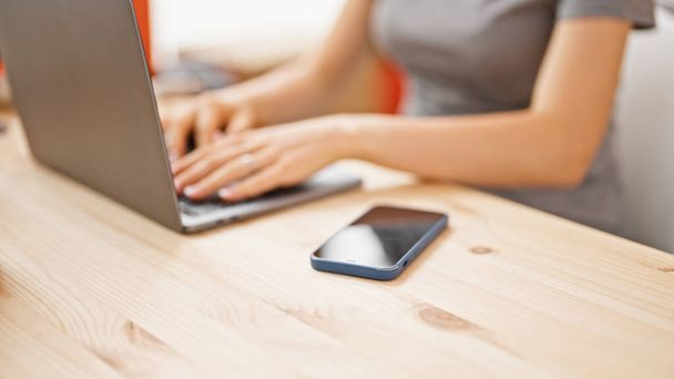 Молода блондинка використовує ноутбук, сидячи на столі в офісі - Фото, зображення