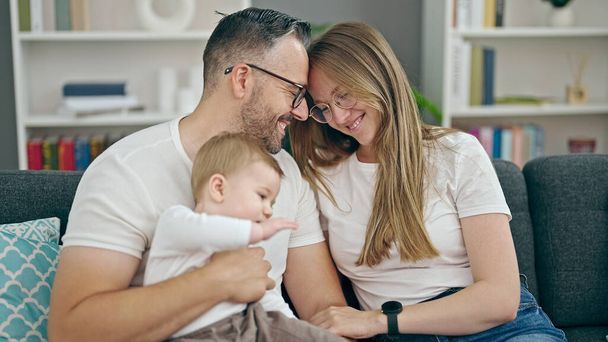 Rodina matky, otce a dítěte usměvavé sedí na pohovce doma - Fotografie, Obrázek