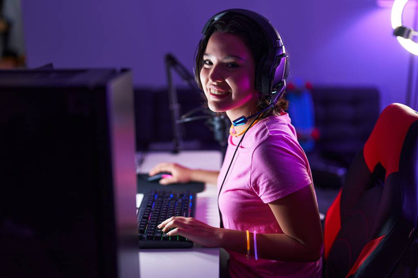 Junge hispanische Streamerin spielt Videospiel mit Computer in Spielothek - Foto, Bild