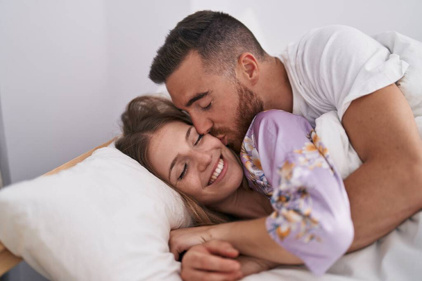 Man and woman couple lying on bed kissing at bedroom - Photo, Image