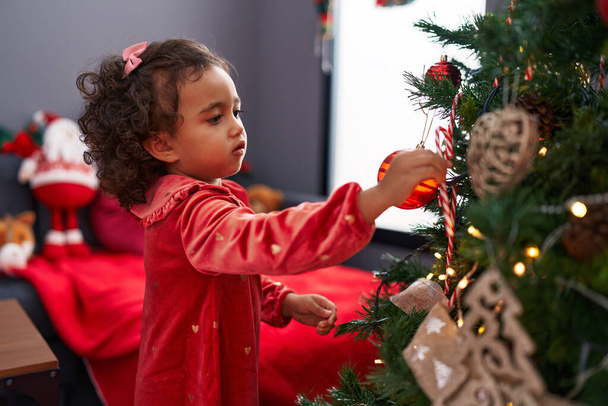 Imádnivaló spanyol lány díszítő karácsonyfa otthon - Fotó, kép