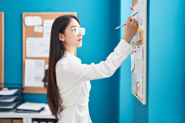 Young chinese woman business worker writing on cork board at office - Foto, Bild