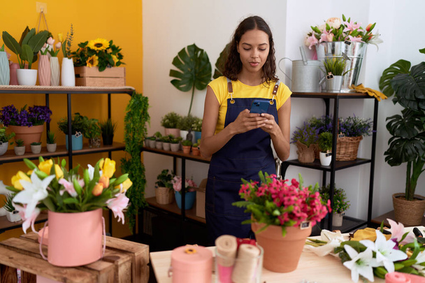 Jeune fleuriste afro-américaine utilisant un smartphone à la boutique de fleurs - Photo, image