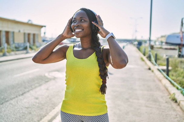 Africano americano mulher vestindo sportswear ouvir música na rua - Foto, Imagem