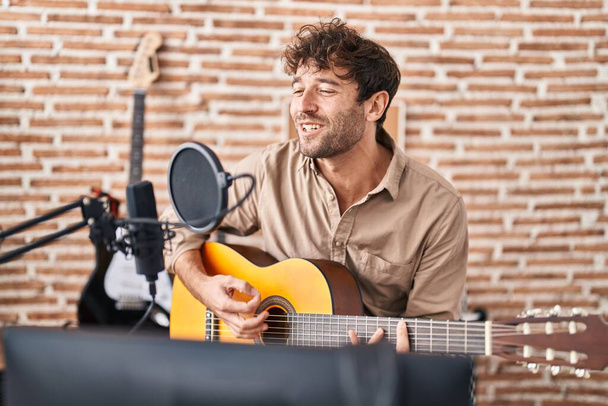 Young man musician singing song playing classical guitar at music studio - Foto, immagini
