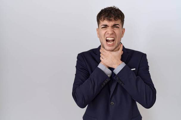 Νεαρός Ισπανός επιχειρηματίας με κοστούμι και γραβάτα να φωνάζει και να ασφυκτιά από οδυνηρό στραγγαλισμό. πρόβλημα υγείας. ασφυξία και έννοια της αυτοκτονίας.  - Φωτογραφία, εικόνα