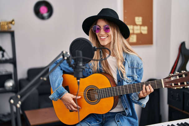 Genç bayan müzisyen müzik stüdyosunda klasik gitar çalarak şarkı söylüyor. - Fotoğraf, Görsel