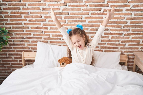 Adorabile ragazza caucasica svegliarsi allungando le braccia in camera da letto - Foto, immagini
