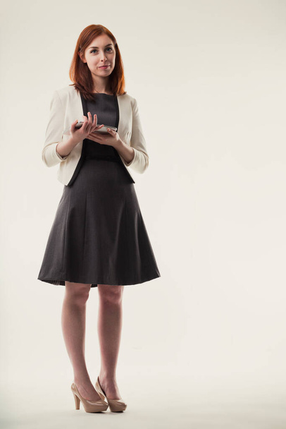 Eleganssi työpaikalla: ammattimainen nainen seisoo älypuhelimellaan, johon sisältyy armo ja liitettävyys - Valokuva, kuva