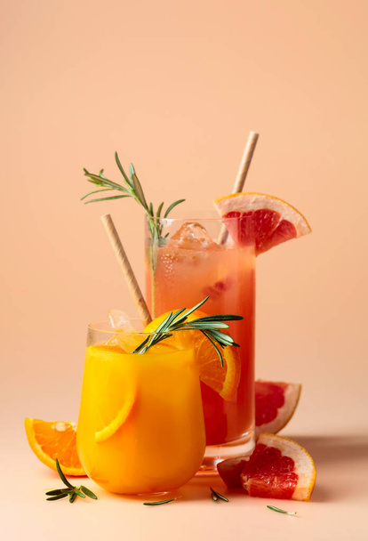 Апельсиновый и грейпфрутовый сок в стаканах с розмарином и льдом. Копирование пространства. - Фото, изображение