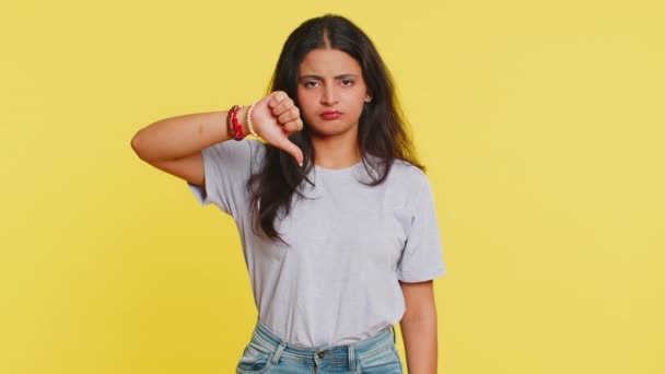 Nem tetszik. Feldúlt, boldogtalan indiai nő mutatja hüvelykujját lefelé jel gesztus, kifejezi elégedetlenség, rosszallás, elégedetlen negatív visszajelzést. Vonzó hindu lány beltéri elszigetelt sárga háttér - Felvétel, videó