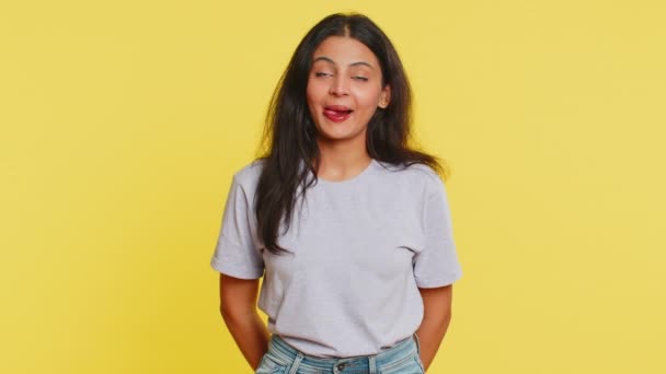 Divertido cómico juguetón indio joven mujer haciendo expresiones faciales tontas muecas tonterías, mostrando lengua, expresión idiota. Comediante chica árabe sobre fondo amarillo. Estilo de vida de la gente - Metraje, vídeo