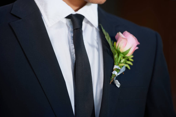 Крупним планом, мода або квітка на весільному костюмі, смокінг або куртка в одязі, коханні або події. Особа, наречений або краватка з рожевою трояндою, рослиною або бутоньєрою на святкування, зобов'язання або романтичний стиль. - Фото, зображення