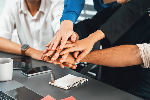 Group of diverse office worker join hand together in office room symbolize business synergy and strong productive teamwork in workplace. Cooperation and unity between business employee. Prudent - Photo, Image