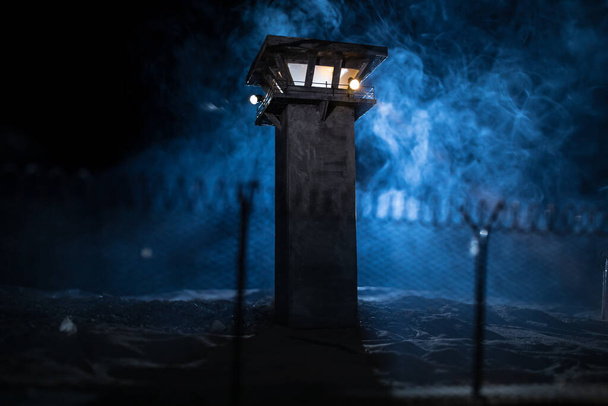 Koncept uvěznění v trestním soudnictví. Stará vězeňská strážní věž chráněná v noci drátem z vězeňského plotu. Kreativní umělecká dekorace. Selektivní zaměření - Fotografie, Obrázek