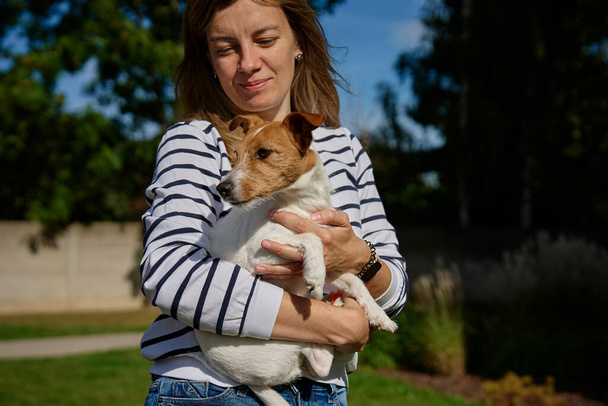 Vrouw heeft plezier met hond. Vrouwelijke eigenaar brengt tijd door samen met huisdier buiten. Vriendschap tussen dier en mens. - Foto, afbeelding