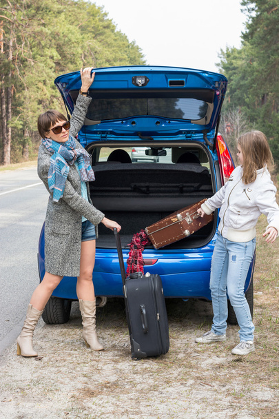 Madre e hija viajando en coche con maletas
. - Foto, imagen