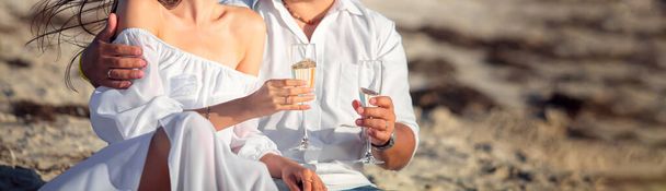 Fiatal szerelmesek, az esküvőjüket ünneplik a parton. Gyönyörű pár iszik pezsgőt. - Fotó, kép