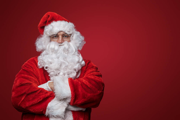 Nachdenklicher Weihnachtsmann mit verschränkten Armen beim Betrachten der Weihnachtszeit - Foto, Bild