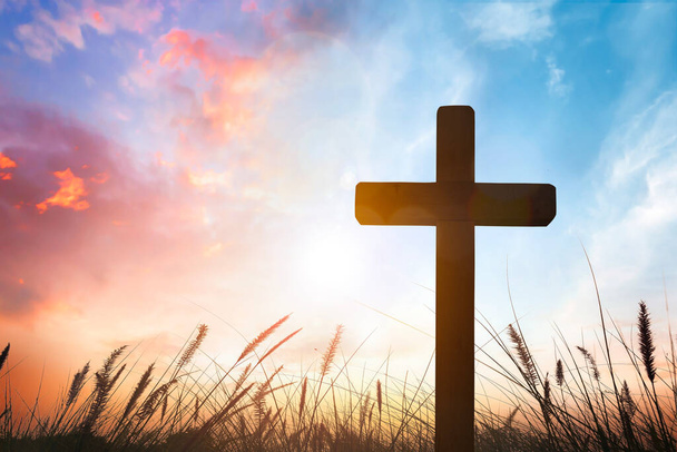 Krzyż na trawie z zachodem słońca w tle nieba - Zdjęcie, obraz