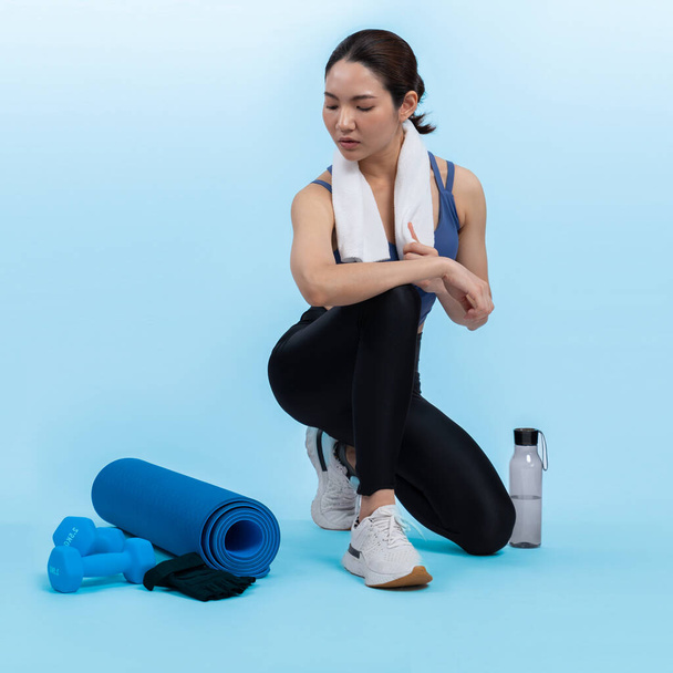 Atletik ve sportif Asyalı kadın yoğun kardiyo antrenmanından sonra dinleniyor. Stüdyoda sağlıklı egzersiz ve vücut bakımına uygun yaşam tarzı takibi izole edilmiş bir arka plan. Kuvvetli - Fotoğraf, Görsel
