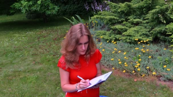 Terhes üzleti nő írás a papír notebook ül a fűben - Felvétel, videó