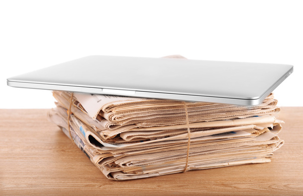 Laptop with stack of newspapers on table on white background - Φωτογραφία, εικόνα