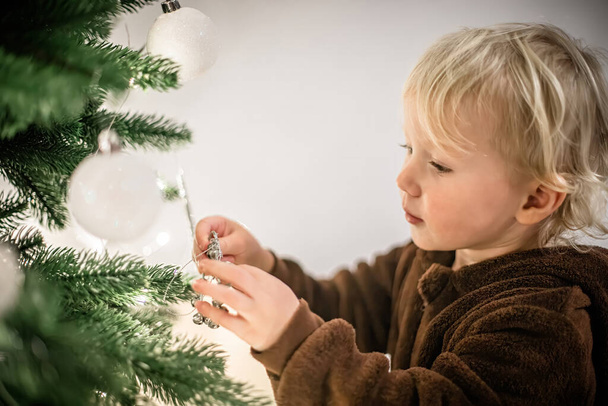 Petite fille mignonne jouant avec l'arbre de Noël à la maison dans le salon - Photo, image